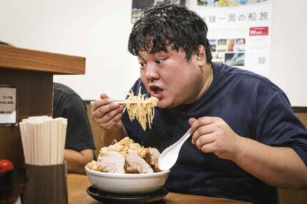 大盛ラーメンをほおばる恰幅の良い男性